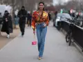 Stylische Frau in bunten Jackett und bootcut jeans kombinieren mit pinker Tasche und auffälligen Schuhen.