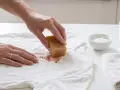 Hand reibt mit Gallseife über einen braunen Fleck auf weißem T-Shirt, um gewaschene Blutflecken entfernen zu können.
