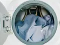 Blaue Wäsche in einer offenen Waschmaschine. Die Frage, ob Polyester einlaufen kann, beschäftigt viele.