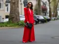 Frau in rotem Hosenanzug mit pinkem Top und Clutch mit Lippenmotiv. Was passt zu roter Hose? Dieser Look zeigt es!
