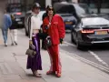 Zwei Personen präsentieren ihren **new money style** auf der Straße: glitzernder lila Rock, rote Jacke und sportliche Elemente.