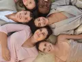 Sechs lächelnde Menschen liegen eng beieinander. Ihre Kleidung, wie ein beiger Anzug und ein rosafarbenes Kleid, inspiriert die Idee einer leichten basisgarderobe sommertyp.