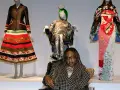 Bei einer Vernissage werden extravagante Kleider auf Schaufensterpuppen präsentiert. Eine Frau im Rollstuhl sitzt davor.