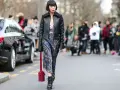 Frau im typisch 90er Grunge Style mit Lederjacke, geblümtem Kleid und Stiefeln. Ein roter Nietenbeutel rundet den Look ab.