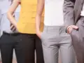 Vier Personen in Business-Kleidung stehen nebeneinander, Hände in den Hosentaschen.