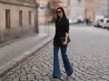 Stylische Frau in Schlaghosen und schwarzem Blazer. Ein tolles Beispiel, welche Oberteile zu Schlaghosen passen: elegant und modern.