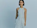 Ein Model trägt ein weißes Spitzenkleid mit Blumenapplikationen. Welche Farbe passt zu Himmelblau? Dieses Kleid ist eine zarte Antwort.