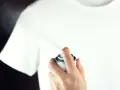 Hand sprüht mit einer Dose auf ein weißes T-Shirt, um statische Aufladung zu verhindern.