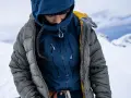 Person in Daunenjacke in winterlicher Berglandschaft. Die Daunenjacke waschen ist wichtig für die Langlebigkeit.
