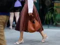 Elegant brauner Faltenrock, kombiniert mit weißer Bluse und cognacfarbener Tasche. Ein stilvoller Look für den Sommer.