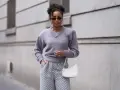 Eine Frau in grauem Pullover und Hose mit Zickzackmuster. Sie trägt eine weiße Tasche. Ein Beispiel, welche Farben passen zu grau.