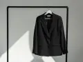 Schwarzer Blazer hängt auf einem Kleiderbügel. Zeit, den Blazer zu waschen und frisch zu machen.
