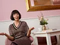 Eine Frau mit Bob-Frisur und einem gemusterten Kleid gestikuliert fröhlich. Sie strahlt Selbstbewusstsein aus, was bedeutet, dass sie feminin ist.