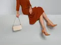 Elegantes Outfit für die Oper: Ein rostbraunes Kleid, cremefarbene Tasche und braune Pumps. So zieht man in die Oper an.