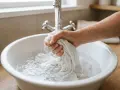 Hand wäscht ein weißes Tuch in einer Spüle, um hartnäckige blut flecken entfernen.