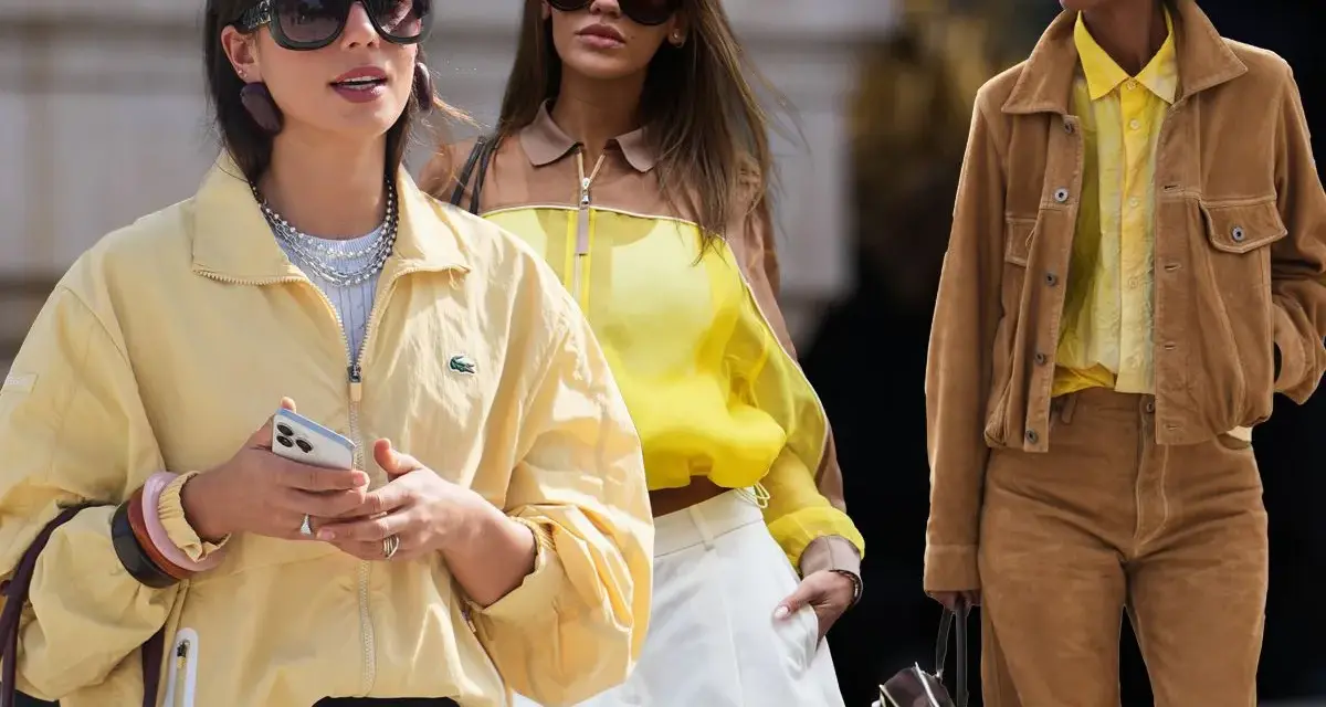 Drei Frauen in modischen Outfits. Die vordere trägt eine gelbe Jacke, die mittlere ein gelbes Top. Welche Farbe passt zu Gelb? Braun, wie die Jacke der rechten Frau, ist eine tolle Wahl.