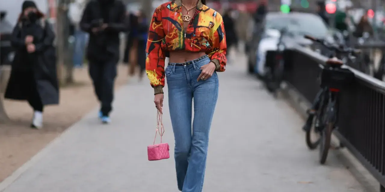 Stylische Frau in bunten Jackett und bootcut jeans kombinieren mit pinker Tasche und auffälligen Schuhen.