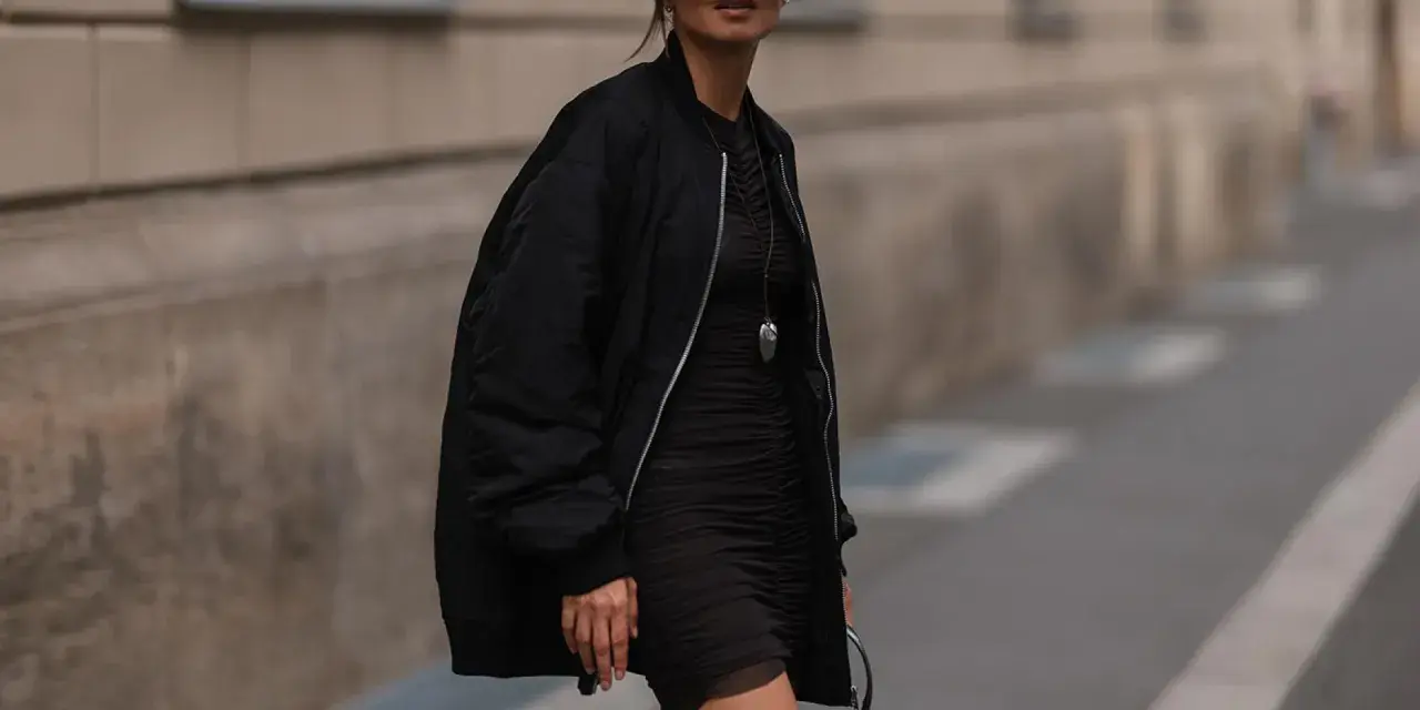Stylische Frau in schwarzer Bomberjacke und engem Kleid. So kann man eine Bomberjacke kombinieren, Damen!
