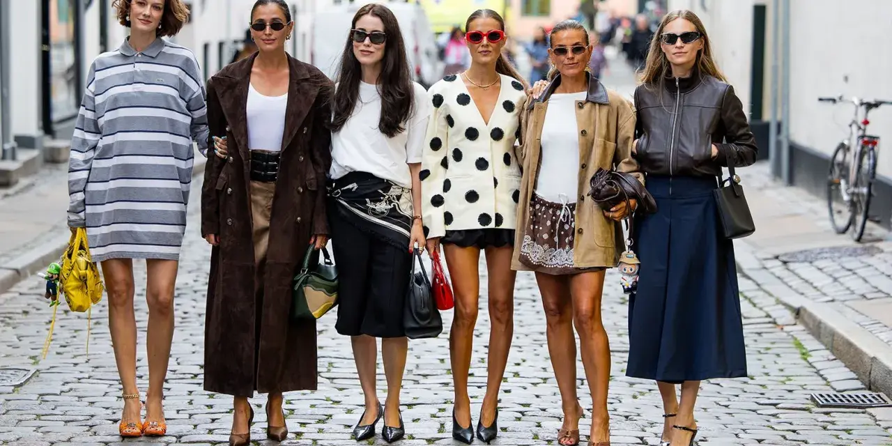 Sechs Frauen präsentieren ihren **scandi look** auf Kopfsteinpflaster. Von gestreiften Kleidern bis zu Lederjacken – ein vielfältiger Stilmix.