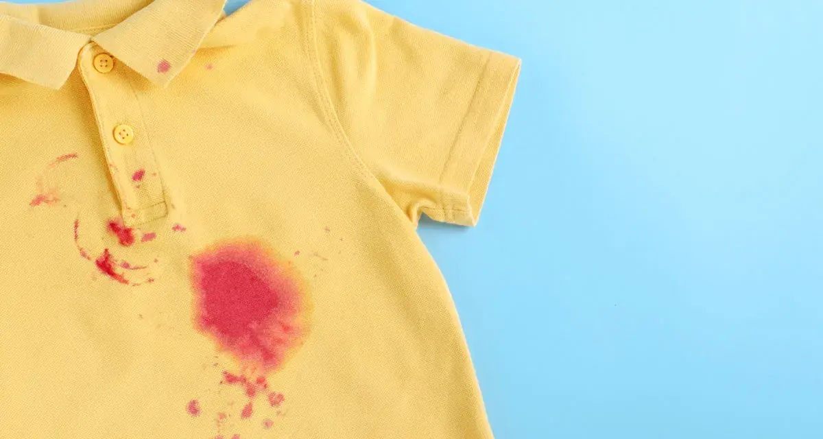 Gelbes Poloshirt mit roten Flecken, die nach dem Entfernen von Kleidung suchen.