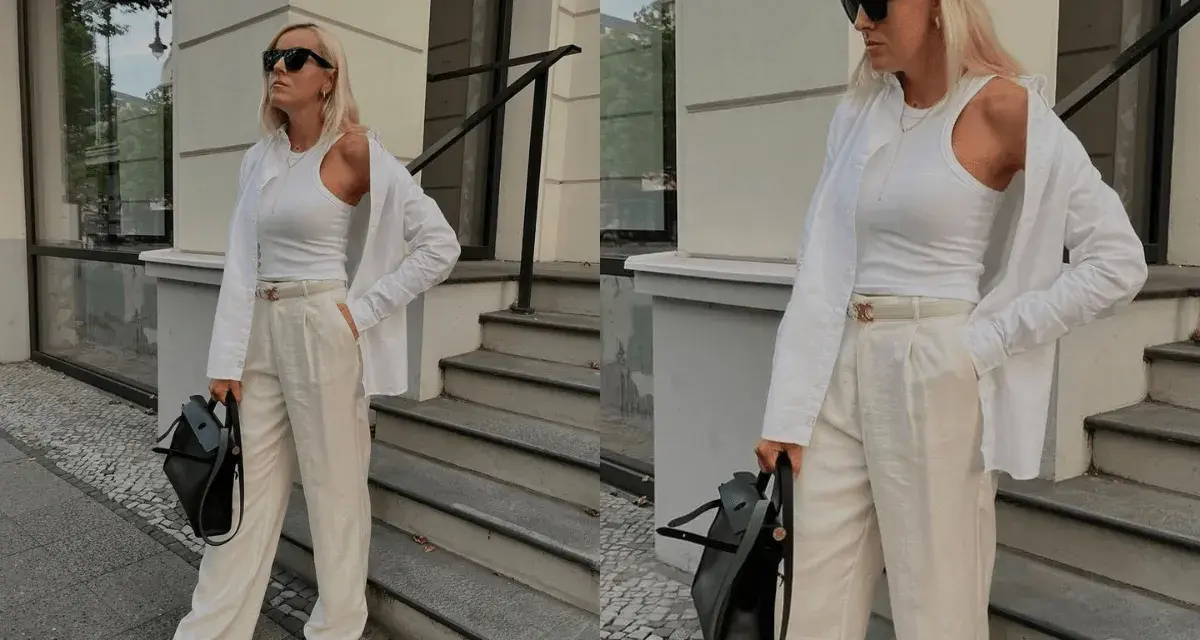 Eine Frau im Stil von quiet luxury, gekleidet in weiße Kleidung, steht vor einer Treppe.