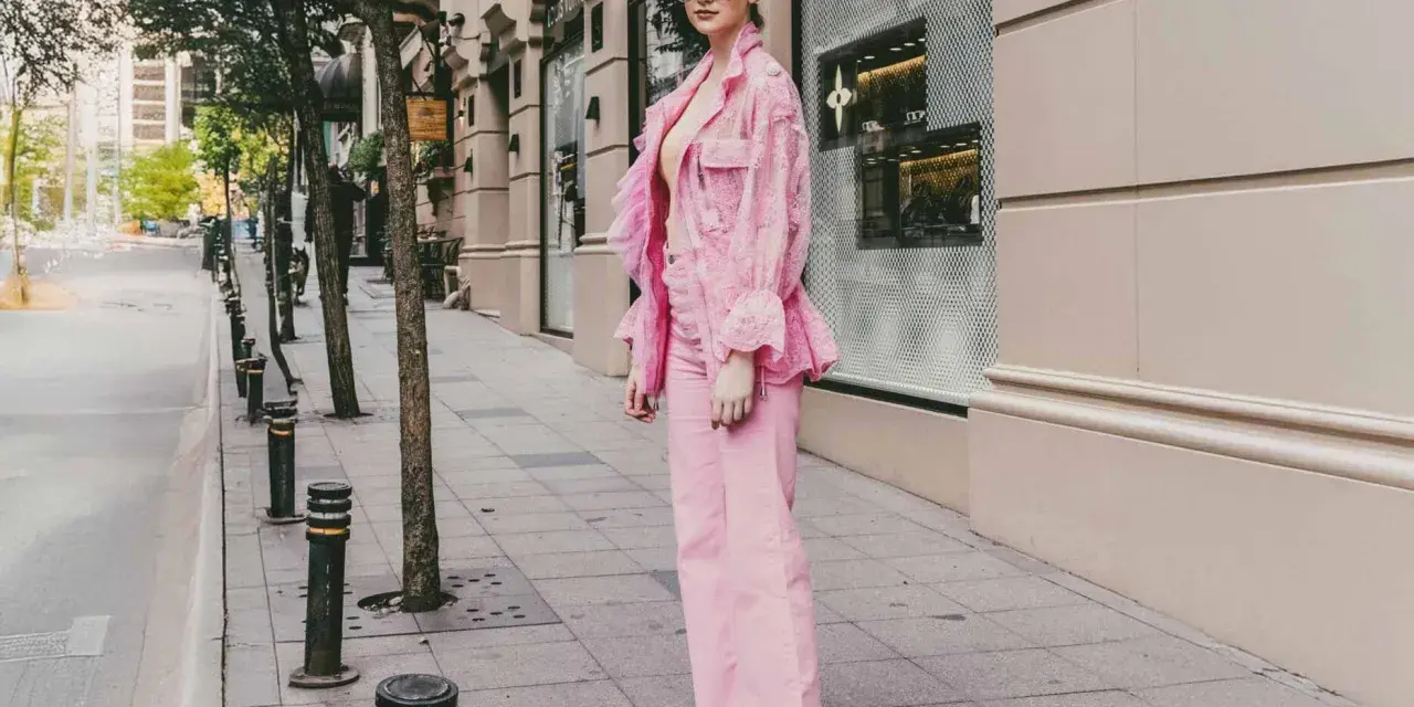 Eine Frau in einem auffälligen Outfit mit pinker Hose und passender Jacke. Ein modisches Statement, wie man pinke Hose kombinieren kann.
