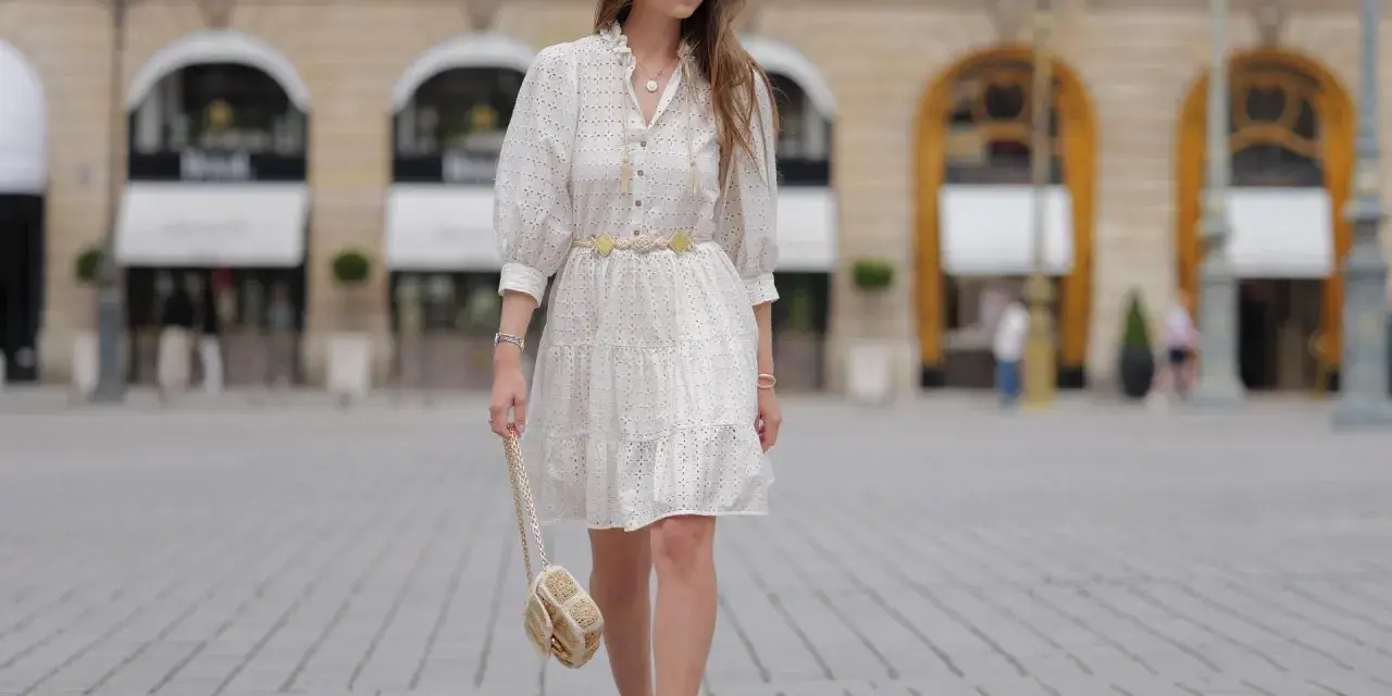 Sommerliches Outfit für eine Gartenparty: Weißes Lochstick-Kleid, goldener Gürtel, Sandalen und eine kleine Umhängetasche.