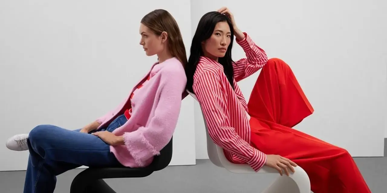 Zwei Frauen in leuchtenden Farben, ein Beispiel für Dopamin Dressing. Eine trägt einen pinken Cardigan, die andere ein rot-weiß gestreiftes Hemd und weite rote Hosen.
