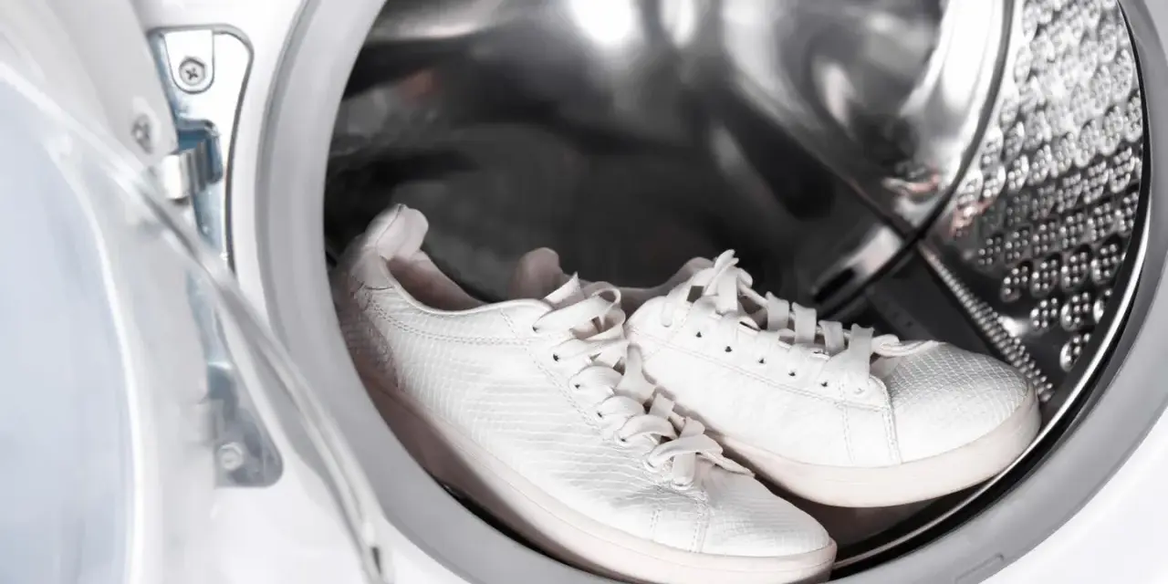 Weiße Sneaker warten in der Waschmaschine auf ihre Reinigung.