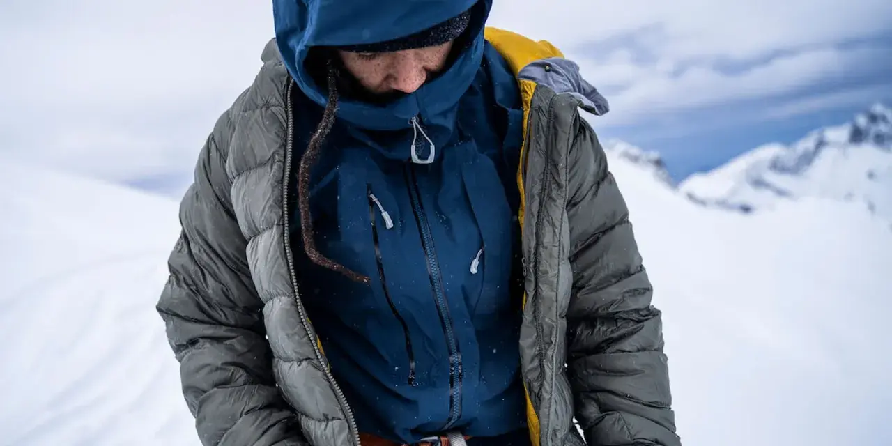 Person in Daunenjacke in winterlicher Berglandschaft. Die Daunenjacke waschen ist wichtig für die Langlebigkeit.