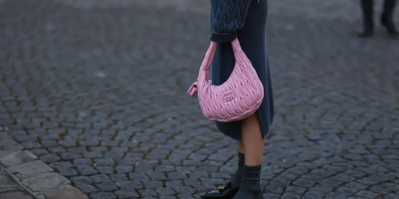 Ein grauer Strickrock kombiniert mit einem Oversize-Pullover und einer pinken Tasche.