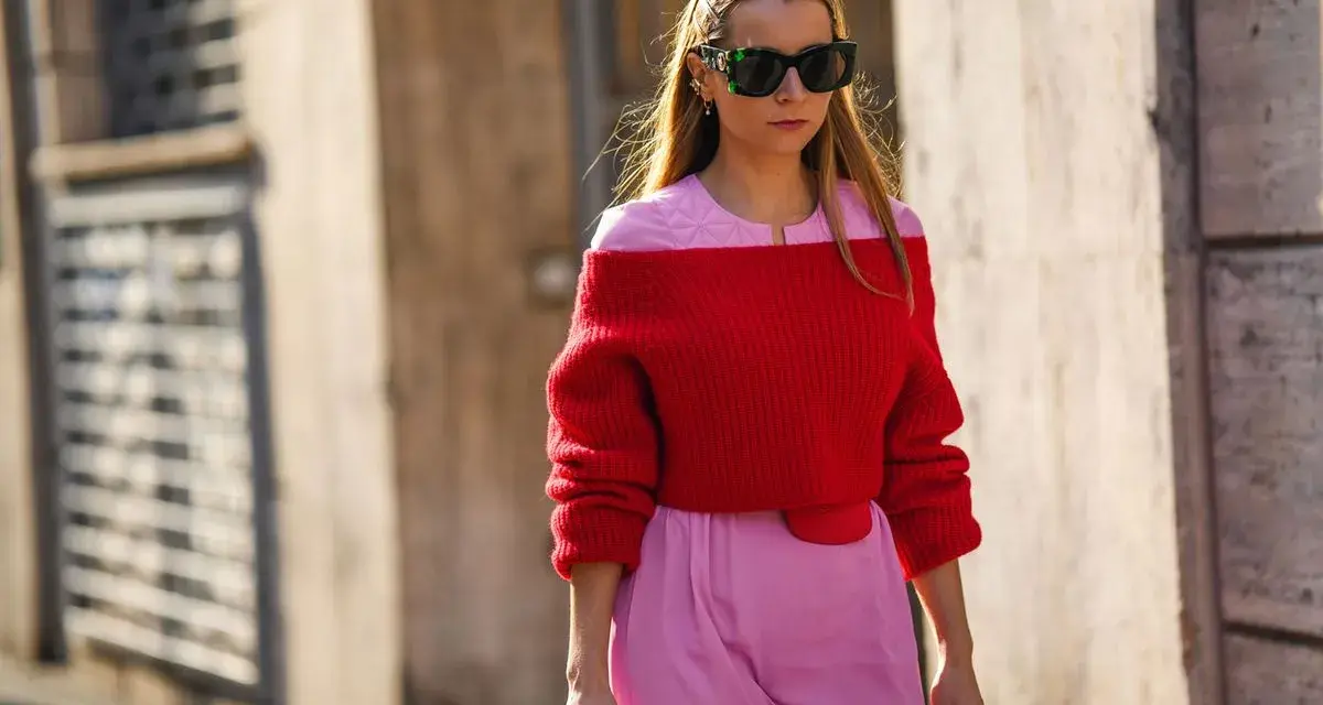 Frau in rotem Off-Shoulder-Pullover und rosa Hose. Eine tolle Farbkombination, die zeigt, welche Farbe passt zu roter Kleidung: Rosa!