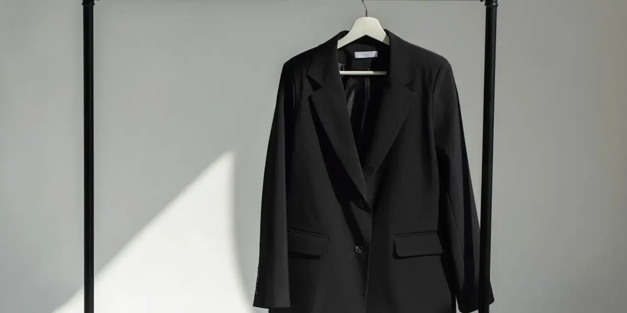 Schwarzer Blazer hängt auf einem Kleiderbügel. Zeit, den Blazer zu waschen und frisch zu machen.