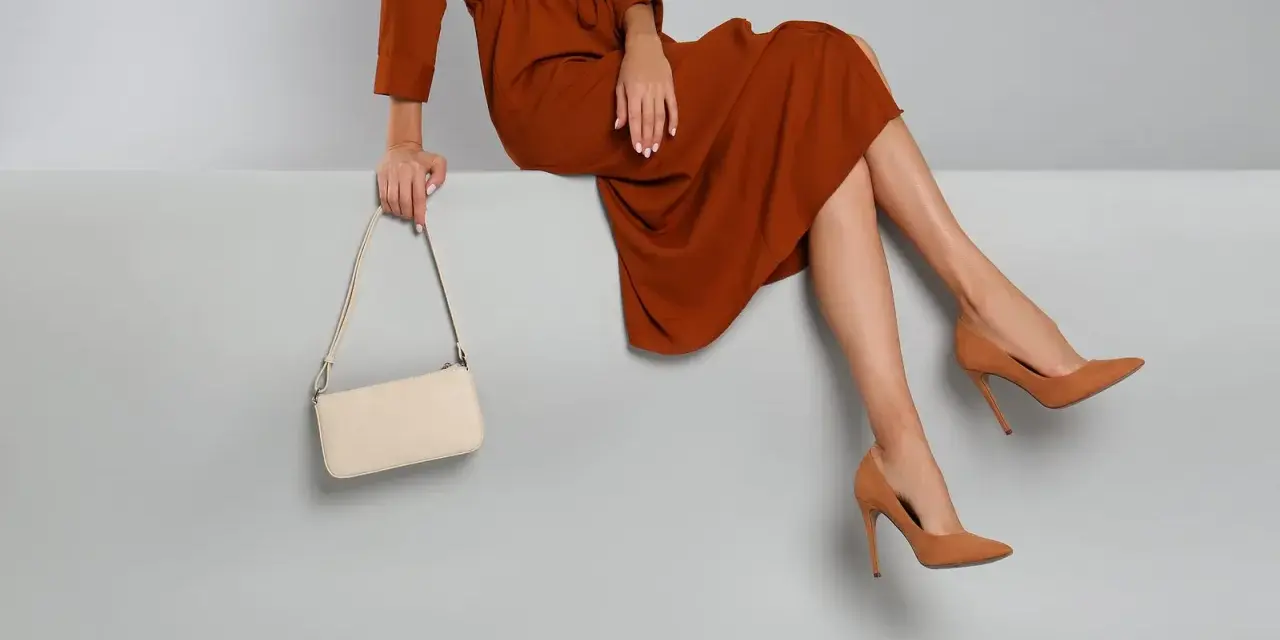 Elegantes Outfit für die Oper: Ein rostbraunes Kleid, cremefarbene Tasche und braune Pumps. So zieht man in die Oper an.
