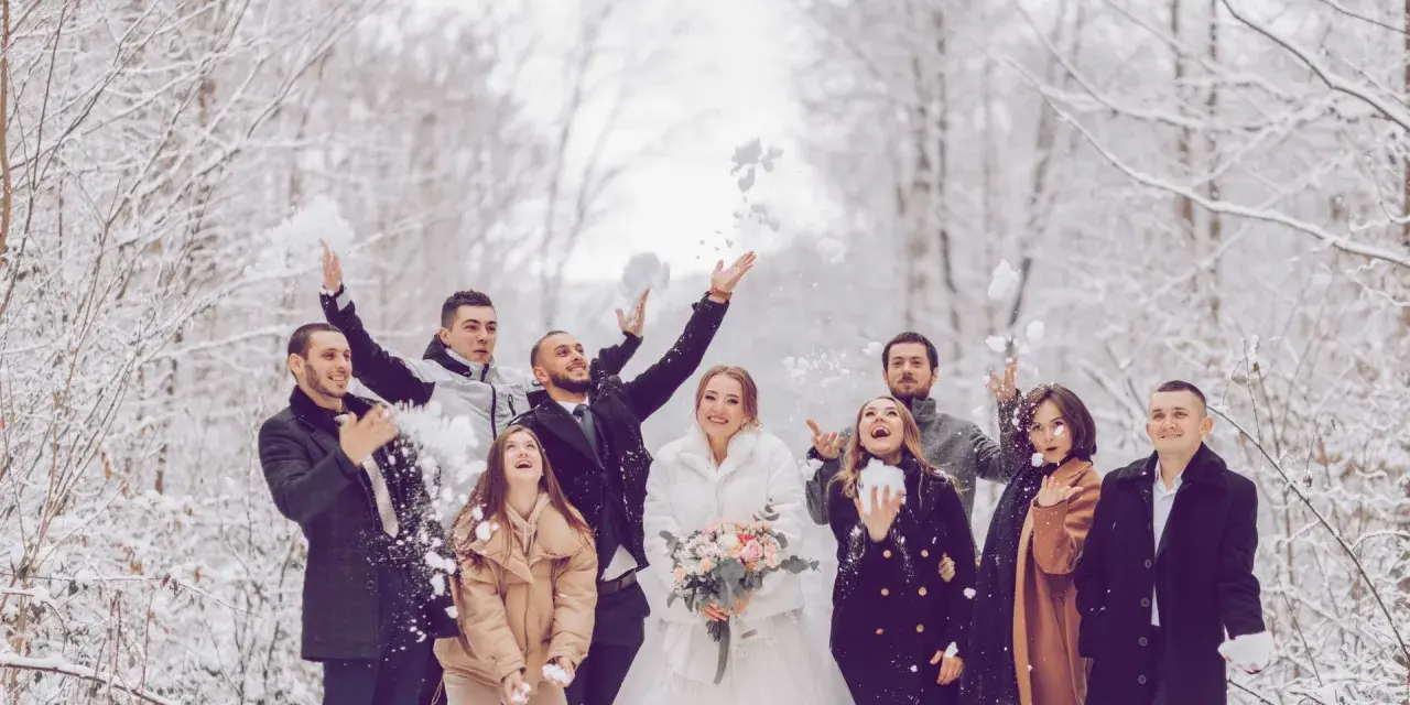Fröhliche Gäste werfen Schnee in der Luft. Das Brautpaar strahlt, während die Gäste ihr silberhochzeit outfit tragen.