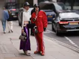 Zwei Personen präsentieren ihren **new money style** auf der Straße: glitzernder lila Rock, rote Jacke und sportliche Elemente.