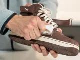 Hände reinigen braune Wildleder Schuhe mit einer Bürste. So werden die Lieblingssneaker wieder wie neu.