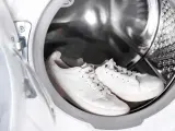 Weiße Sneaker warten in der Waschmaschine auf ihre Reinigung.