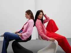 Zwei Frauen in leuchtenden Farben, ein Beispiel für Dopamin Dressing. Eine trägt einen pinken Cardigan, die andere ein rot-weiß gestreiftes Hemd und weite rote Hosen.