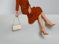 Elegantes Outfit für die Oper: Ein rostbraunes Kleid, cremefarbene Tasche und braune Pumps. So zieht man in die Oper an.