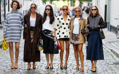 Sechs Frauen präsentieren ihren **scandi look** auf Kopfsteinpflaster. Von gestreiften Kleidern bis zu Lederjacken – ein vielfältiger Stilmix.