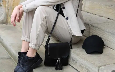 Stylisches flugzeug outfit damen: beige Hose, Blazer, schwarze Sneaker, Tasche und Cap. Perfekt für die Reise.