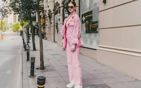 Eine Frau in einem auffälligen Outfit mit pinker Hose und passender Jacke. Ein modisches Statement, wie man pinke Hose kombinieren kann.