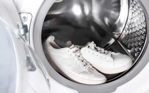 Weiße Sneaker warten in der Waschmaschine auf ihre Reinigung.