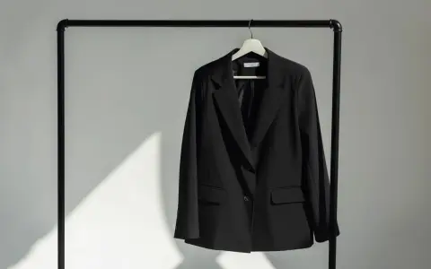Schwarzer Blazer hängt auf einem Kleiderbügel. Zeit, den Blazer zu waschen und frisch zu machen.