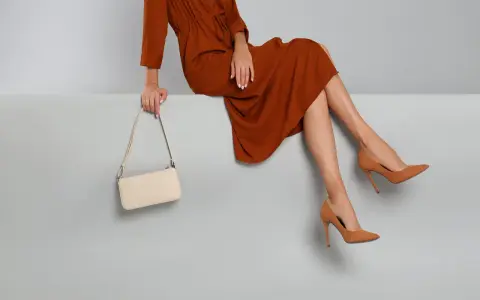 Elegantes Outfit für die Oper: Ein rostbraunes Kleid, cremefarbene Tasche und braune Pumps. So zieht man in die Oper an.