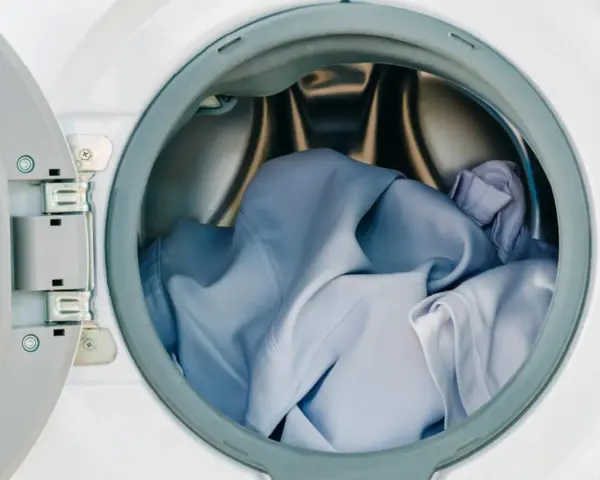 Blaue Wäsche in einer offenen Waschmaschine. Die Frage, ob Polyester einlaufen kann, beschäftigt viele.