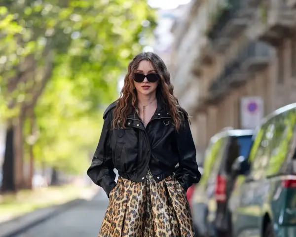 Frau mit langen Haaren trägt eine Lederjacke und einen auffälligen Leo Rock. Sie kombiniert den Leo Rock mit lässiger Eleganz.