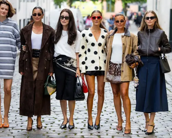 Sechs Frauen präsentieren ihren **scandi look** auf Kopfsteinpflaster. Von gestreiften Kleidern bis zu Lederjacken – ein vielfältiger Stilmix.