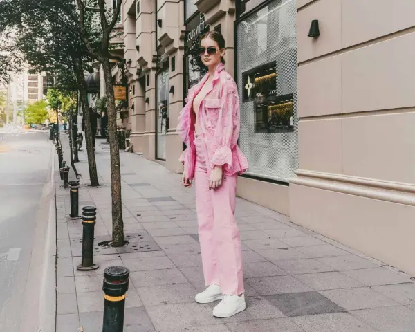 Eine Frau in einem auffälligen Outfit mit pinker Hose und passender Jacke. Ein modisches Statement, wie man pinke Hose kombinieren kann.
